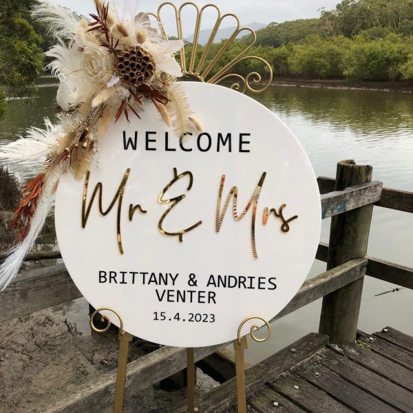 A white sign with gold lettering personalised for a wedding